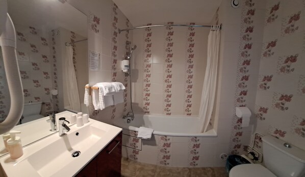 Un baño con lavamanos, espejo, cortina de ducha e inodoro.