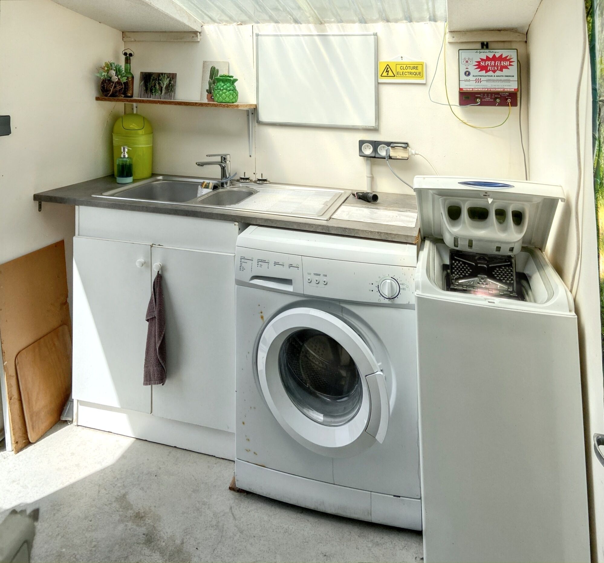 Une cuisine de taille réduite équipée d’un lave-linge, d’un évier et d’un petit réfrigérateur.