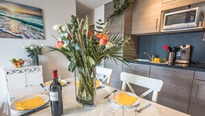A dining table set with plates, cutlery, a wine bottle, and a vase of flowers. - Cozy apartment offering an exceptional location - 1st sea line - swimming pool (Biscarrosse)