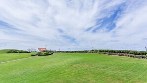 A large, open grassy field with a building in the background. - Cozy apartment offering an exceptional location - 1st sea line - swimming pool (Biscarrosse)