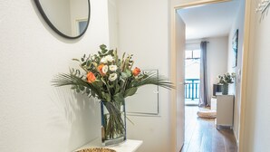 A hallway with a white console table, a mirror, and a vase of flowers. - Cozy apartment offering an exceptional location - 1st sea line - swimming pool (Biscarrosse)