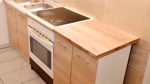 A modern kitchen with wooden cabinets, a stainless steel sink, and a built-in oven. - Lorabel Apartmanház Hévíz (Hévíz)