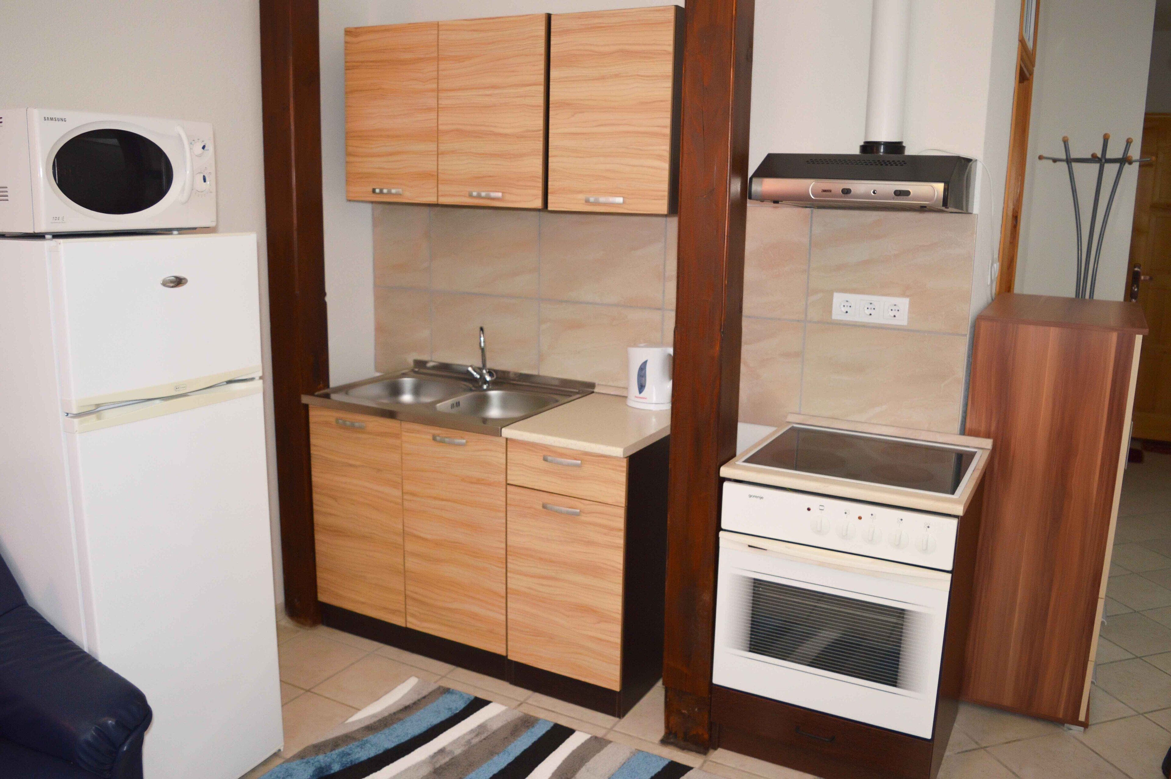 A compact kitchen with wooden cabinets, a built-in microwave, a sink, and a stove.