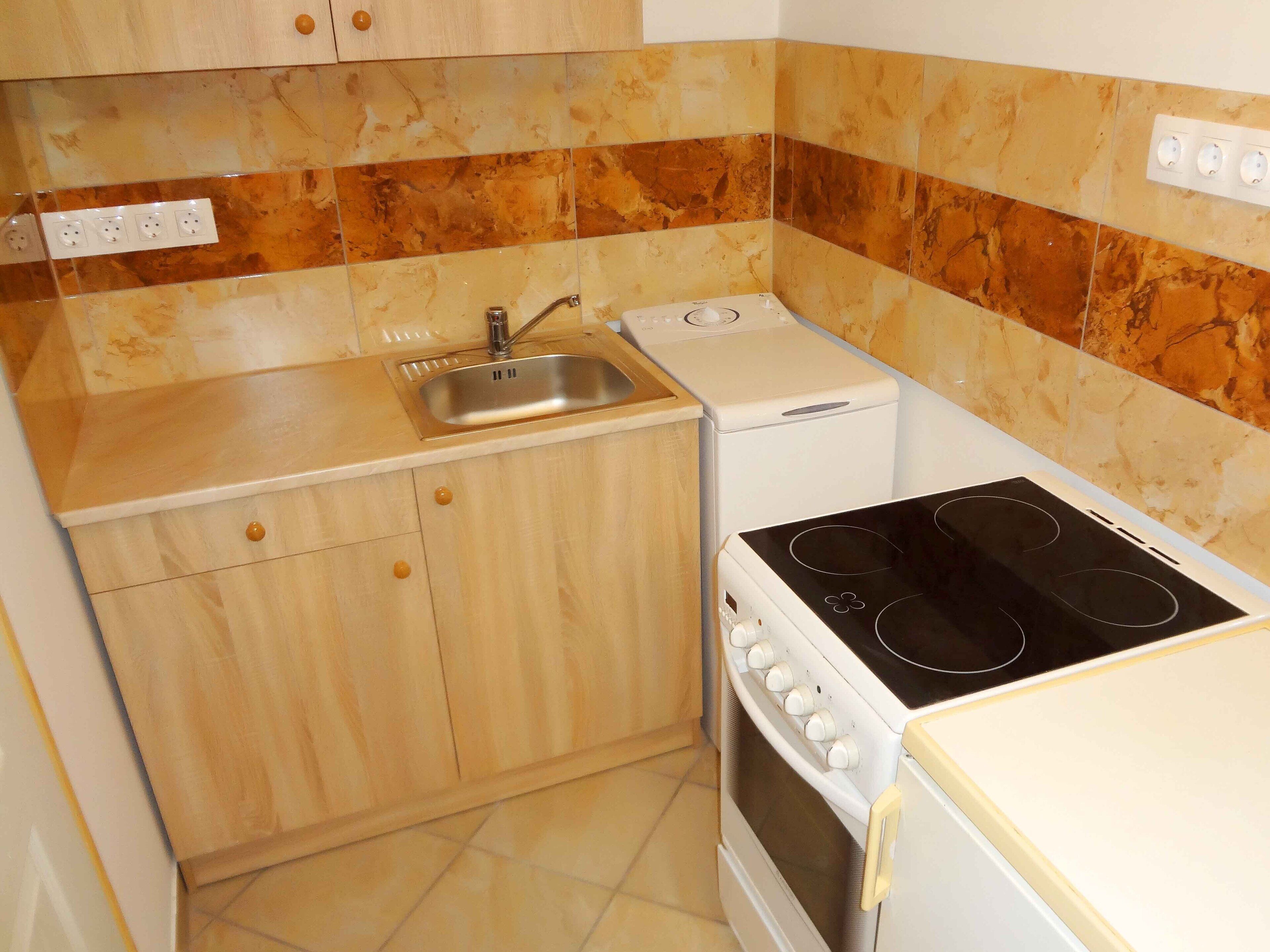 Una cocina compacta con un lavabo, estufa y lavadora pequeña.