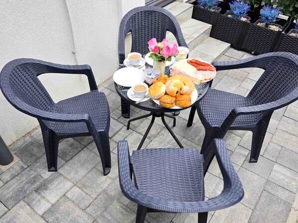 A table set with chairs, plates of food, and a cup of coffee.