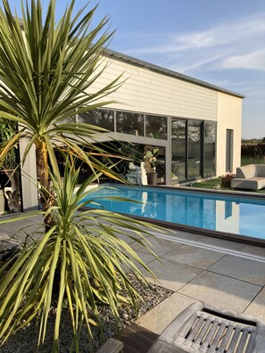 Ein modernes Haus mit Swimmingpool, großen Fenstern und einem gepflegten Garten.