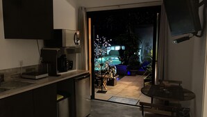 A modern kitchen with a built-in microwave, coffee maker, and dishwasher. There is a small dining table and a bench in the adjacent area. - Desir'Add (La Clisse)