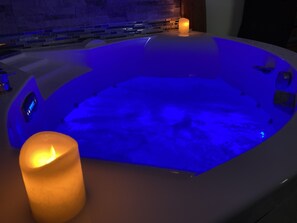 A hot tub with blue lighting and a lit candle. - Desir'Add (La Clisse)