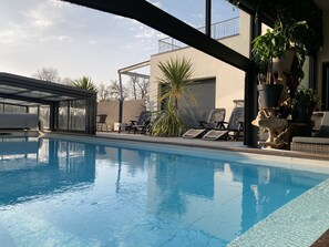 A swimming pool with lounge chairs and potted plants.