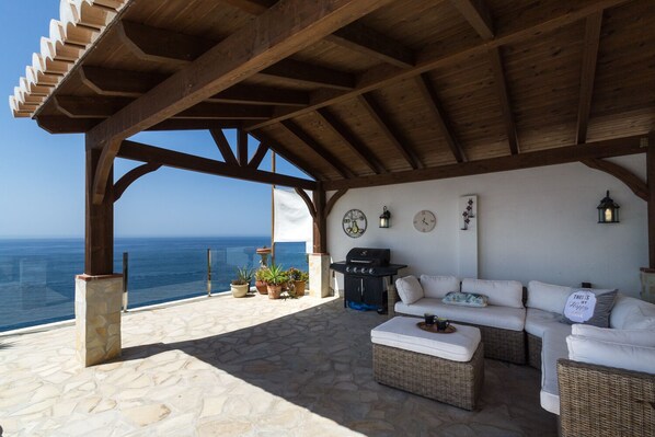A covered outdoor seating area with a view of the sea, stone flooring, and a barbecue grill. - Villa Casa Tomise with private swimming pool and fantastic views (Salobreña)
