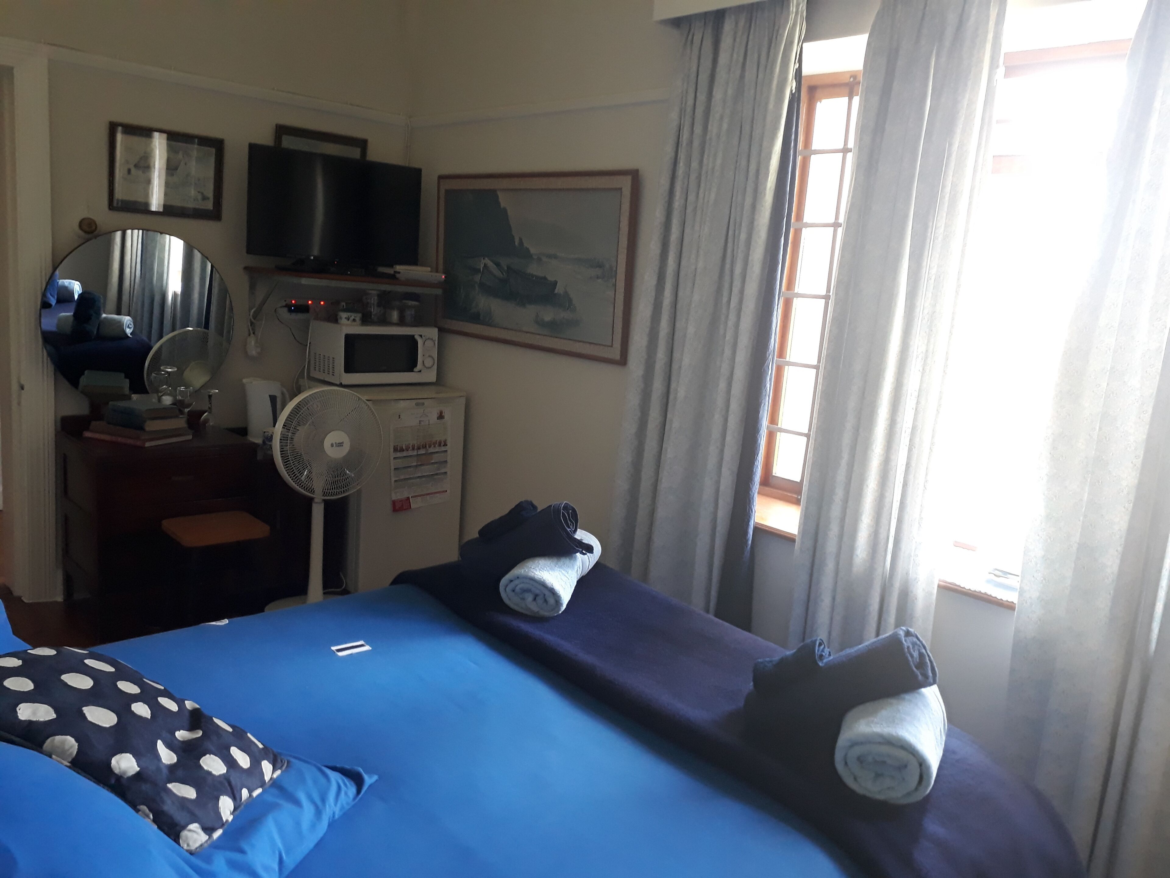 Ein Hotelzimmer mit Bett, Fernseher, Mikrowelle, Ventilator und einem Fenster mit Vorhängen.
