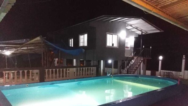 A swimming pool adjacent to a building with a balcony and stairs leading to an upper level.