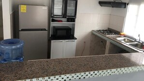 A compact kitchen with a refrigerator, microwave, and gas stove.
