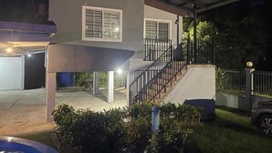 A two-story house with a covered garage and a staircase leading to the upper floor.