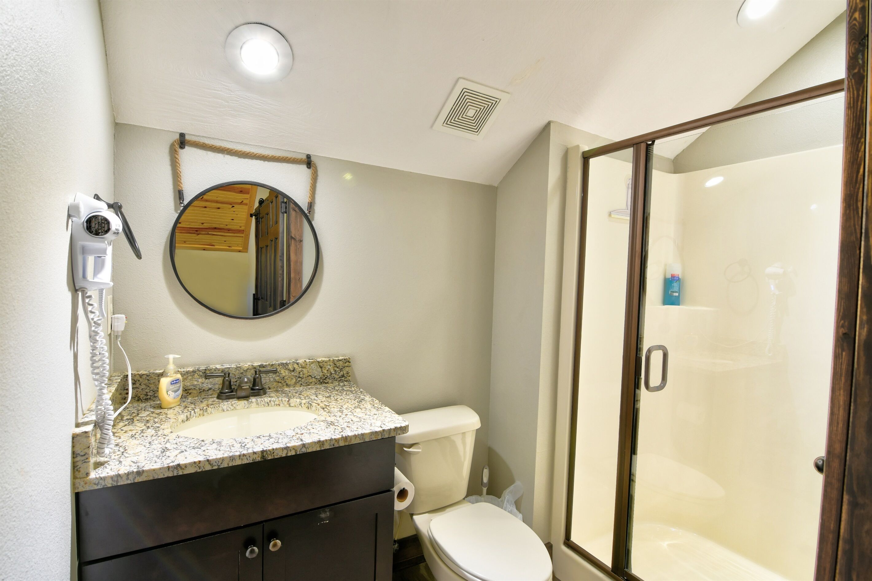 A bathroom with a sink, mirror, toilet, and a glass-enclosed shower.