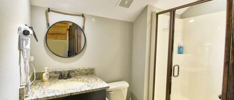 A bathroom with a sink, mirror, toilet, and a glass-enclosed shower.