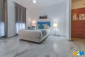 A modern hotel room with a large bed, a bedside table, a lamp, and a wall-mounted artwork.