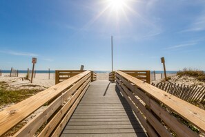 A wooden boardwalk leading to a beach with a 'Stay Off Dunes' sign.