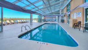 An indoor swimming pool with clear blue water, sun loungers, and a glass ceiling. - Bahama Sands 1106, 3 BR Ocean Front Luxury Condo with Indoor Outdoor Swimming Pool, Hot Tub, Lazy River and Kiddie Pool (North Myrtle Beach)