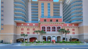 A multi-story hotel with a central red building flanked by two curved structures. - Bahama Sands 1106, 3 BR Ocean Front Luxury Condo with Indoor Outdoor Swimming Pool, Hot Tub, Lazy River and Kiddie Pool (North Myrtle Beach)
