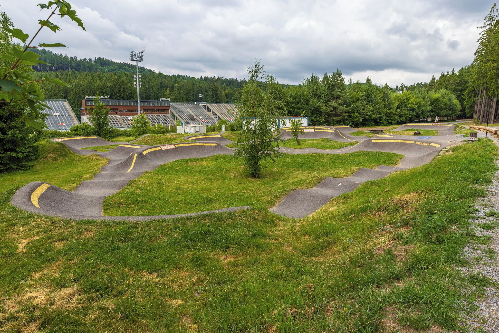 A park with a winding track, a small tree, and a building with solar panels in the background.