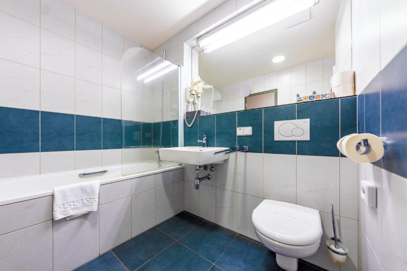 A bathroom with a white sink, a toilet, and a shower area.