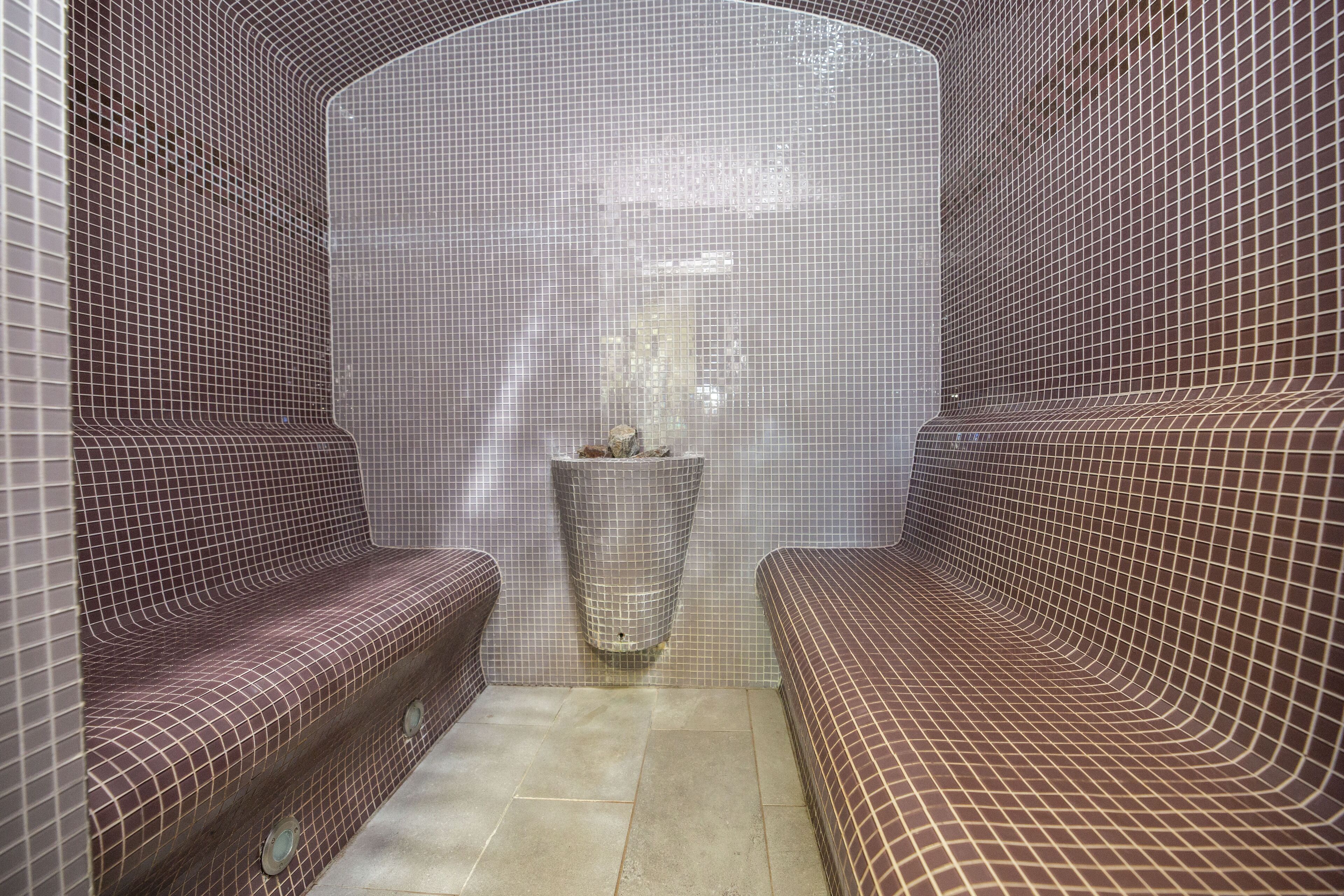 A spa room with tiled walls, a central fountain, and two seating areas.