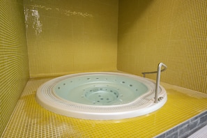 A hot tub with a circular design, surrounded by yellow-tiled walls.
