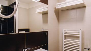 A bathroom with a white sink, a mirror, a hairdryer, a towel rack, and a radiator.