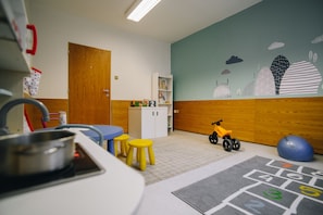 A children's playroom with a hopscotch game, a toy motorcycle, and a bookshelf. - Hotel Ski (Nové Mesto na Morave)