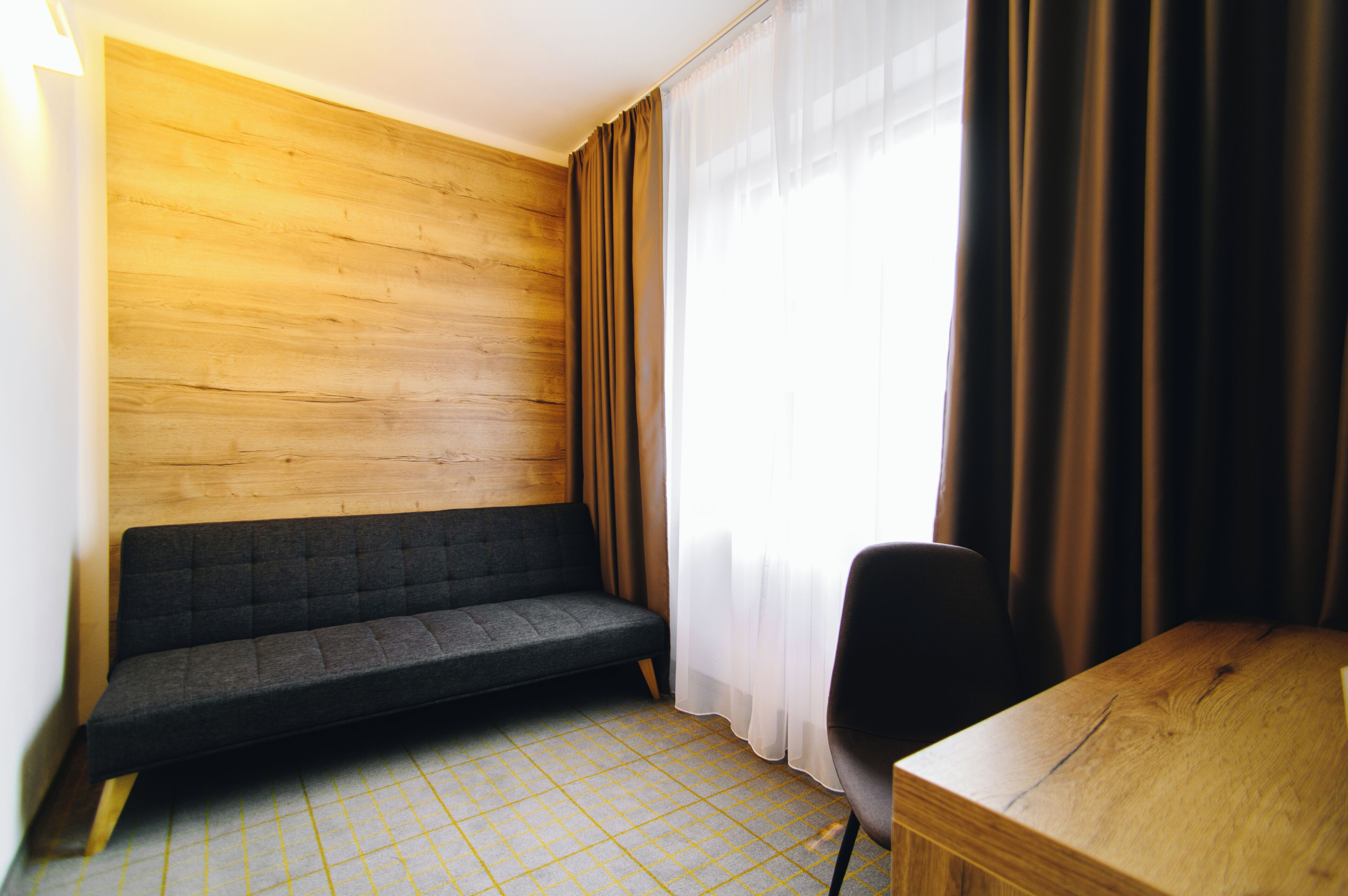 A room with a wooden wall, a sofa, a chair, and a table.