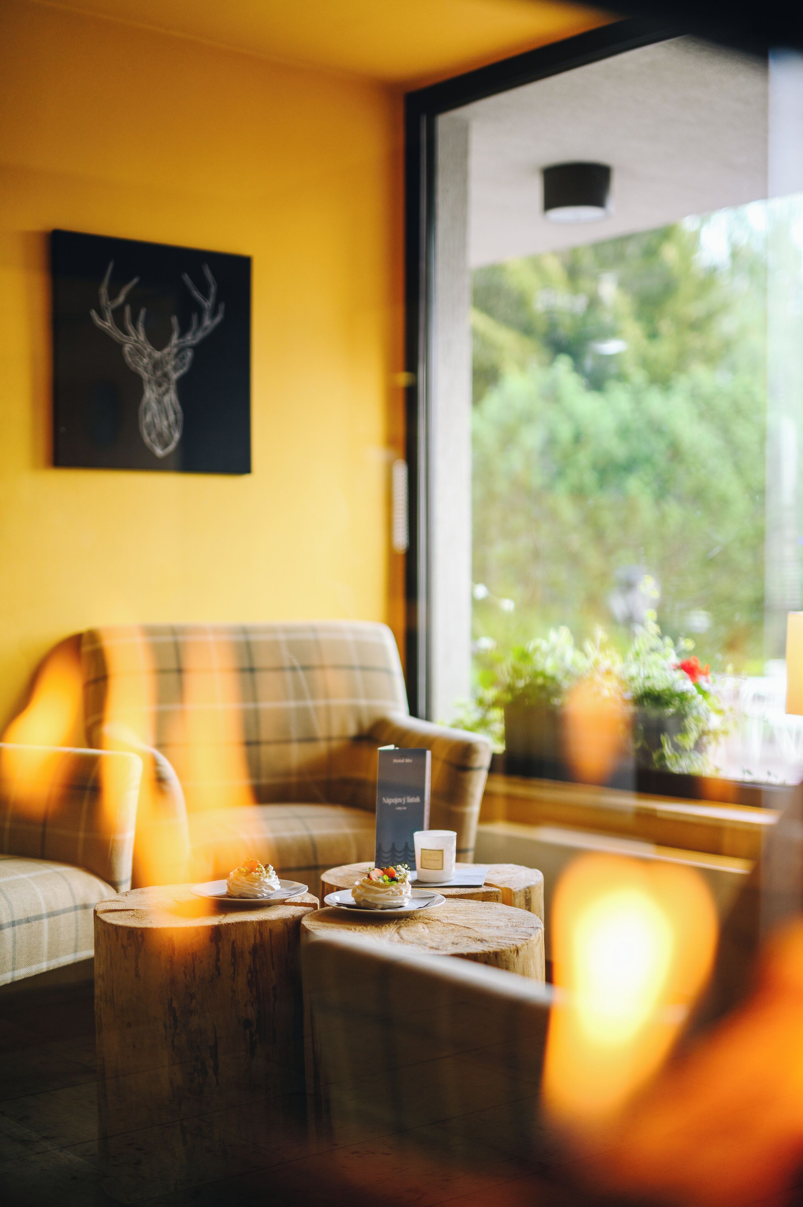 A cozy room with a sofa, a wooden table with candles, and a window with a view of greenery.