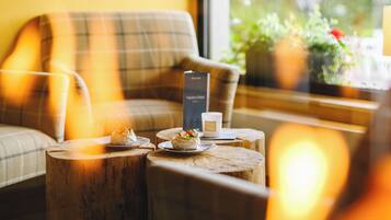 A cozy room with a sofa, a wooden table with candles, and a window with a view of greenery.