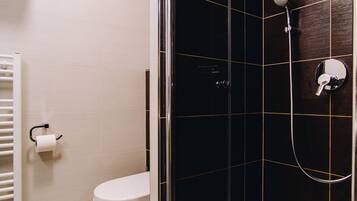 Un baño moderno con ducha envuelta en vidrio, un inodoro y un perchero para toallas.