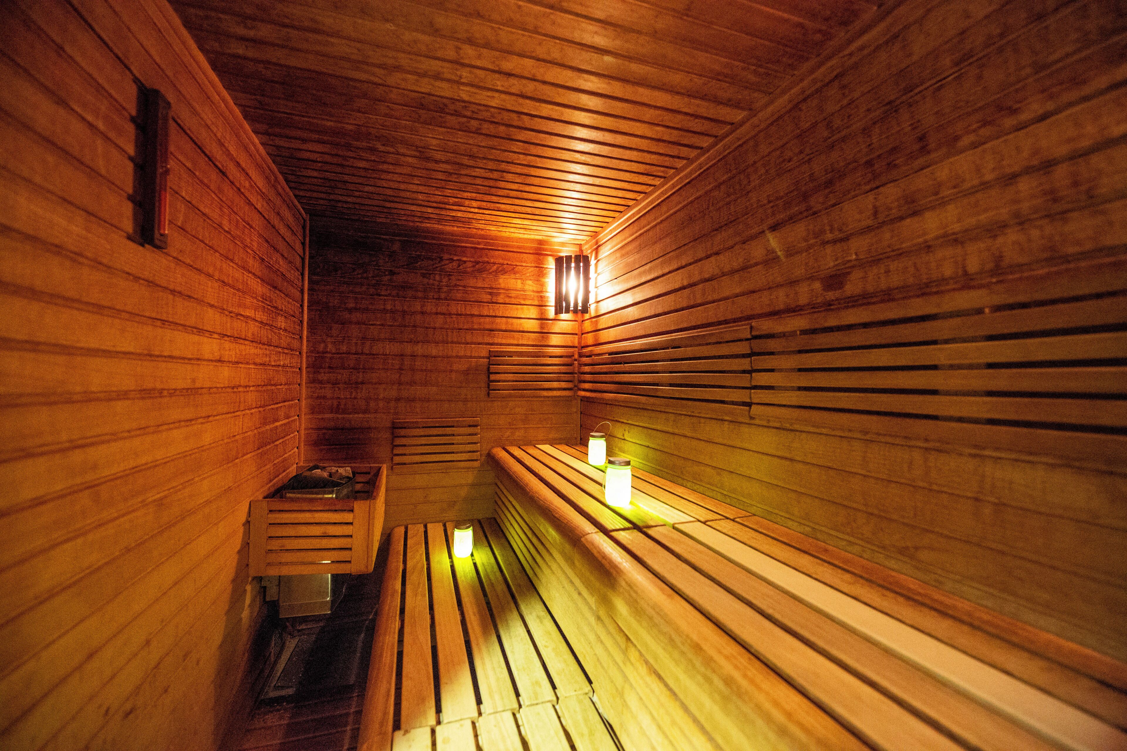 A wooden sauna with benches and wall-mounted lights.