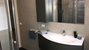 A modern bathroom with a curved sink, a large mirror, and a shower enclosure. - Lorenzo House Venice Mestre (Venezia)