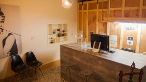 A reception desk with a wooden counter, two black chairs, a small table, and a wall-mounted shelf with items. - Summer night (Tainan)