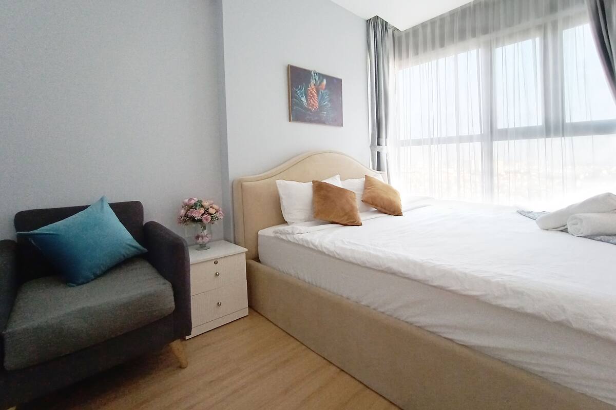 Une chambre d’hôtel avec un lit, une table de chevet, un vase de fleurs et un tableau au mur.