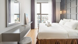 A modern hotel room with a large bed, a desk, and a view of the city through large windows. - Millennium Masteri Apartment (Ho Chi Minh City)