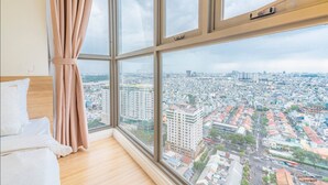 A room with a large window overlooking a cityscape, a bed, and a curtain. - Millennium Masteri Apartment (Ho Chi Minh City)