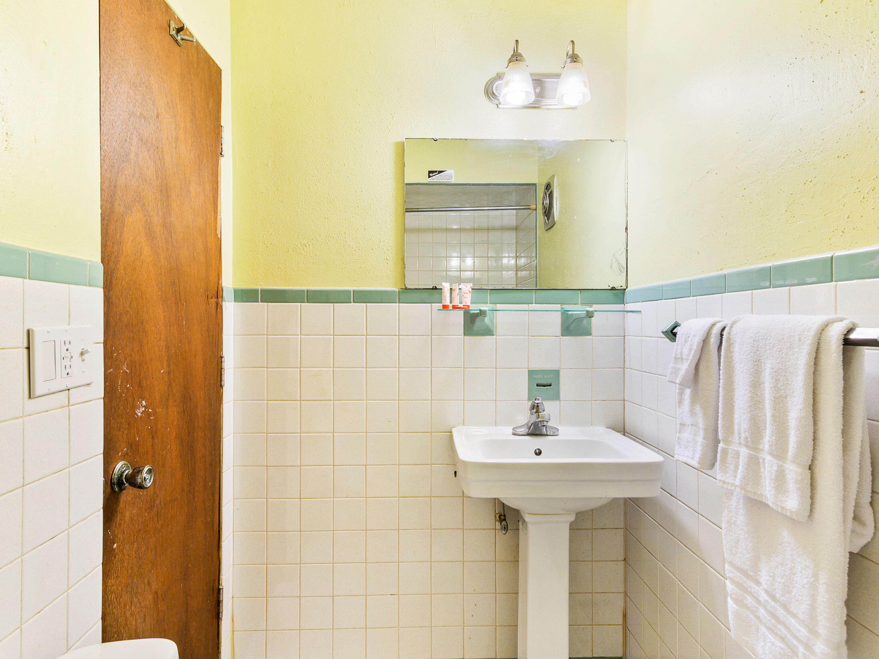 A bathroom with a sink, mirror, and towel rack.