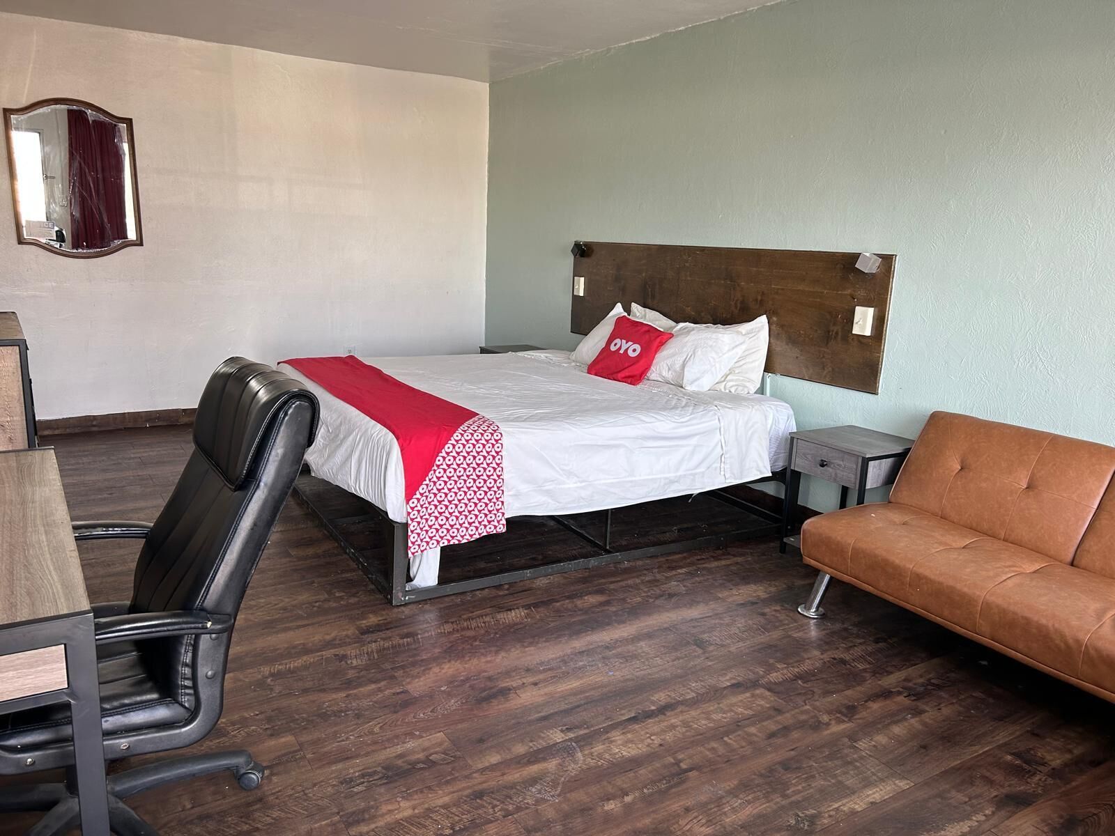 A hotel room with a bed, a desk, a chair, and a sofa.