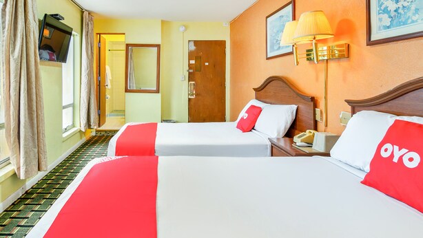 A hotel room with two beds, a television, a telephone, and a painting on the wall. - OYO Hotel Downtown Peoria I-74 (Peoria)