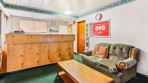 A reception area with a wooden counter, a couch, and a bench. - OYO Hotel Downtown Peoria I-74 (Peoria)