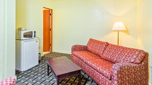 A compact room with a sofa, a small table, a microwave, and a lamp. - OYO Hotel Downtown Peoria I-74 (Peoria)