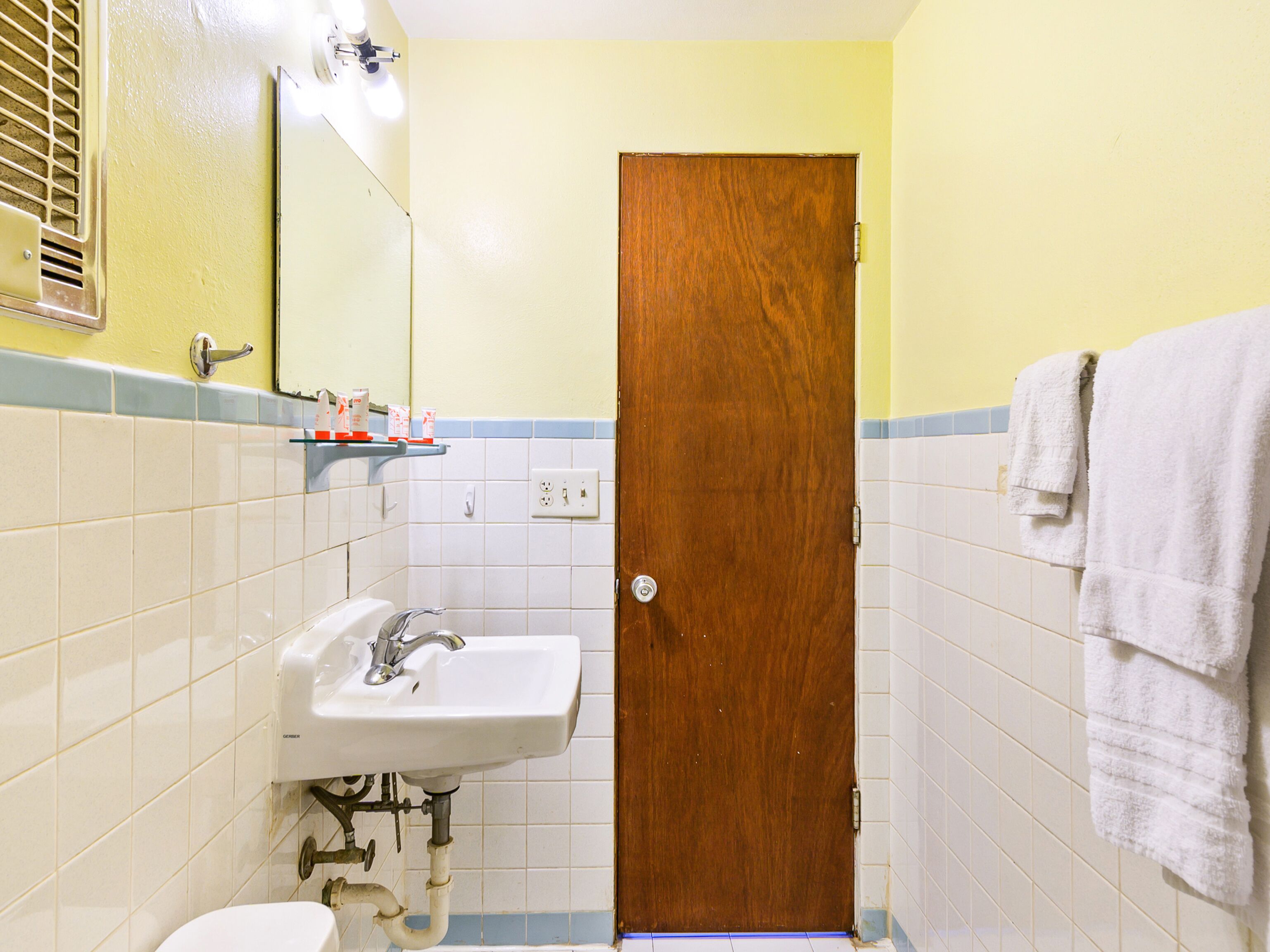 A bathroom with a sink, mirror, and wooden door.