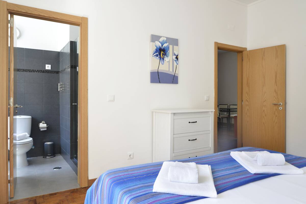 Habitación de hotel con cama, baño y puerta de madera.