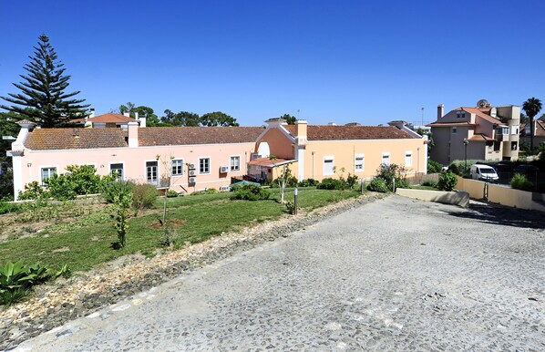 Stylish residential building with a flat roof, set amidst a well-manicured lawn and gravel driveway.