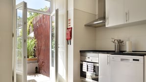 A kitchen with an open door leading to a balcony, a built-in oven, and a dishwasher. - Oeiras  Apartment (Oeiras)