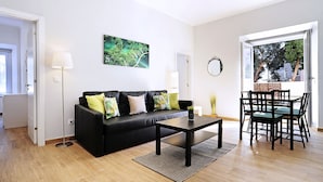 A living room with a black sofa, a coffee table, and a dining table with chairs. - Oeiras  Apartment (Oeiras)
